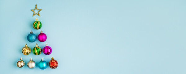 Christmas tree from baubles and golden star on blue pastel background