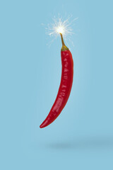 Hot chilli pepper with bomb wick isolated on blue background. Minimal creative composition of...