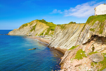 Fototapeta na wymiar View of the cliff of Izurrun beach with its geological limestone rocks forming layers. Zumaya, Euskadi, Spain