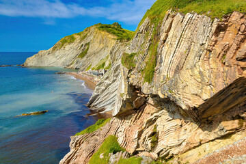 View of the cliff of Izurrun beach with its geological limestone rocks forming layers. Zumaya, Euskadi, Spain