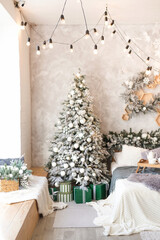 Interior of modern studio living room with comfortable bed decorated with Christmas trees and gifts.