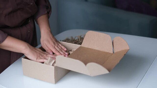woman is packing jars of cosmetics in a box to send a parcel through a delivery service.