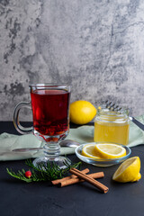 Hot fruit tea with lemon and honey on the dark surface.