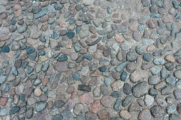 a fragment of a section of a country road made of stones of different sizes and shapes in the...