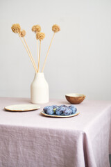 Modern dining table setting. Only natural materials - earthenware, linen textiles, dried flowers. Side view.