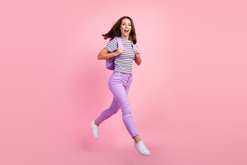 Fototapeta na wymiar Photo of funky charming young lady wear striped outfit backpack smiling jumping high walking isolated pink color background