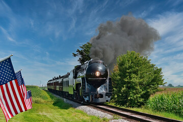 A Antique Restored Steam Engine Approaching Head on Passing a Row of American Flags on a Beautiful...
