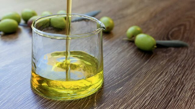 Moroccan organic cold-pressed Extra Virgin Olive Oil is poured into a glass bottle. Background footage healthy eating lifestyle. Slow motion footage.