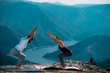 Young couple practice yoga on mountain peak