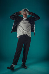 Male beauty concept. Portrait of fashionable young man with stylish haircut wearing trendy glasses and sweater, posing over gray background. Perfect hair & skin. Hipster style. Copy-space. Studio shot