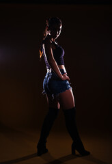 High-contrast silhouette picture of a sexy female model posing on a dark background