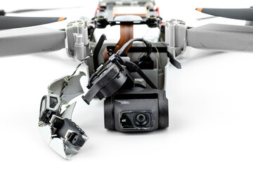 A broken drone after a fall with torn cables and a broken camera, isolated on a white background.