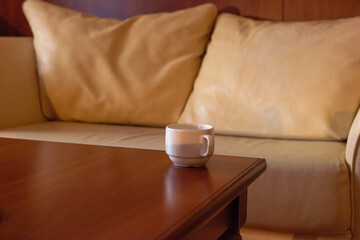 a tea cup on the table, against the background of the sofa cushions in warm colors