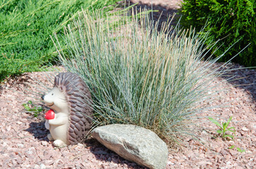 cute hedgehog garden decor. Beautiful Ceramic statue hedgehog on green grass.