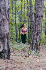 Young athletic sporty girl is jogging outside on a forest path