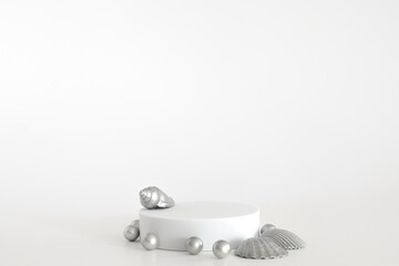 White podium with silver pearls and shells on the white background, simple geometric form. Podium for product, cosmetic presentation. Creative mock up. Pedestal or platform for beauty products.