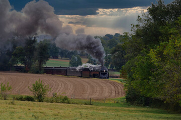 An Antique Steam Engine Approaching With Passenger Coaches on an Overcast Fall Day