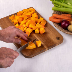 Hands cutting pumpkin with knife on cutting board. Cooking in the kitchen concept. Top view