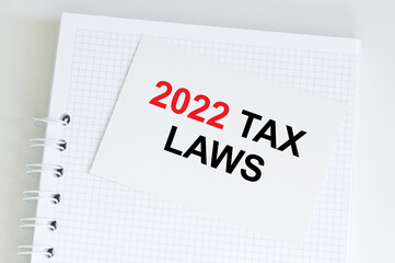 tax 2022 laws text on bright white sticker on notepad, business concept