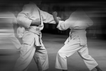 Karate background. Silhouettes of athletes in karate training in retro style with the effect of motion blur.