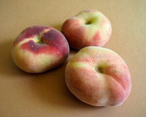 three pink peach figs lie on a brown background. side view. artificially obtained fruits rich in vitamins