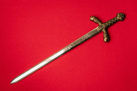 Knight sword close-up on a red background.