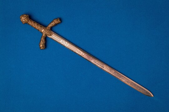 Knight sword close-up on a blue background.