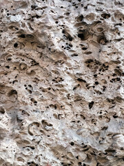 Fragment of a wall of an old house made of sandstone close-up. The texture of a very old stone, treated with wind and rain.