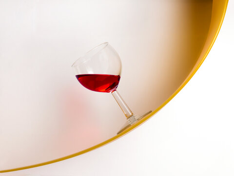 Glass of red wine standing at an angle on a curved shelf