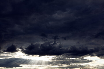 Black clouds with sun rays . Dramatic dark sky with sunlight . Epic heaven