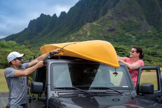 Man and woman fastening a Kayak onto the roof of a car, USA