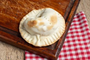 empandas redonda recien horneada sobre tabla de madera