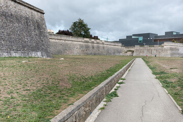 Old city walls with modern building in the background.