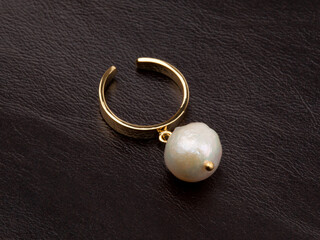 Fototapeta na wymiar Ring with white baroque pearl on brown leather background
