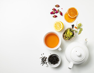 Flat lay a cup of black tea, fruit and herbal tea, with lemon and tea pot on a white background....