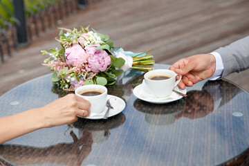 Couple drinking coffee in a cafe restaurant man and woman with a cup of espresso hot cappuccino on dates. Concept of male and female hands of love and coffee.