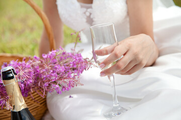 Woman holding a glass of champagne. Bride. Wedding dress. Close up picture. Horizontal format. Outdoor wedding.
