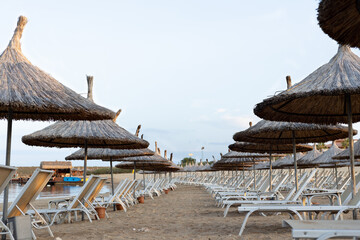 An empty beach with umbrellas and sun beds on the seashore. Without people.