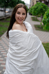 pretty girl in a white blanket walking by the street