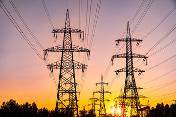 Fototapeta premium Shadows of electical high voltage towers on sunset. Dark electricity power silhouettes.