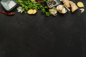 Obraz na płótnie Canvas ingredients spices hot pepper ginger garlic greens on black background on black background 