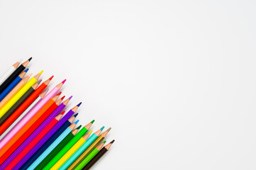 Fototapeta premium Space for creativity: 23 colored wooden crayons against white background. Table top view, flat lay, copy space.