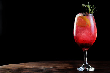 Tasty and refreshing drink of berries with ice, tonic, lemon vodka, gin, tequila and rosemary isolated on black background with space for text