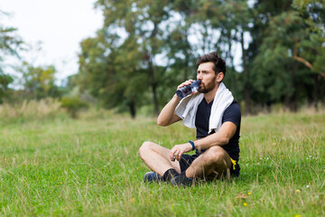 Tired exhausted dehydrated Athlete man runner drinking water bottle after workout. Sports bottle drink. male sportsman. runner sweaty and thirsty after difficult jogging outdoors in city park