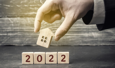 Wooden house in the hands of a businessman and a blocks 2022. Real estate concept. Family budget...