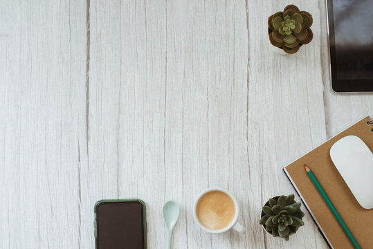 Overhead view of mobile phone, digital table, et, succulents, pencil, notebook and a cup of coffee