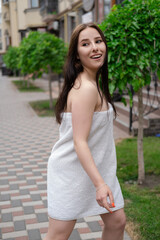 Naklejka premium Attractive girl wrapped in bath towel walks along a city street. Glamorous lifestyle. Fashion shot. Charming young woman is relaxing in spa hotel. New day concept. spa resort