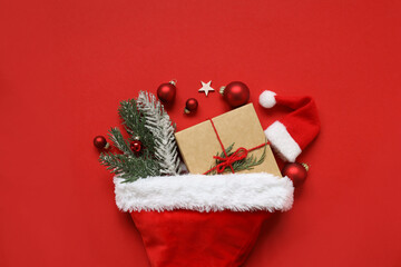 2022 New Year Christmas presents Santa Claus hat with gifts and Christmas decorations on red paper background with copy space. Top view with copy space.