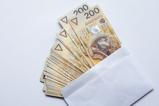 Plik polskich banknot&oacute;w 200 złotych wyłaniający się z białej koperty jako symbol łap&oacute;wki