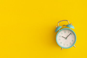 Blue alarm clock on yellow background. Top view with copy space. Flat lay. Back to school concept.